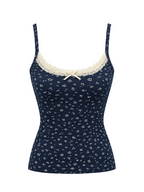 A navy blue camisole top with a small white floral print, featuring cream lace trim along the scoop neckline and a matching cream bow at the center front, displayed on a light gray background.